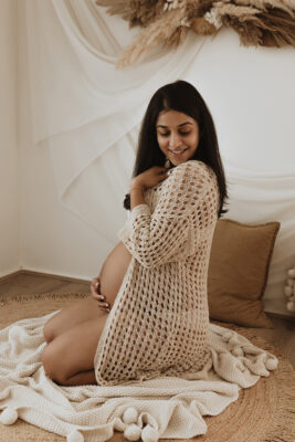 Woman sitting on floor pose holding belly in third trimester waiting for baby